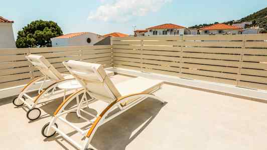 To solsenger på en terrasse med utsikt over hus og trær. (AI-generert tekst)