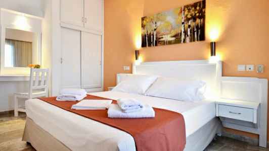 Hotellrom med en dobbeltseng, nattbord, garderobe og et maleri på veggen. (AI-generert tekst)