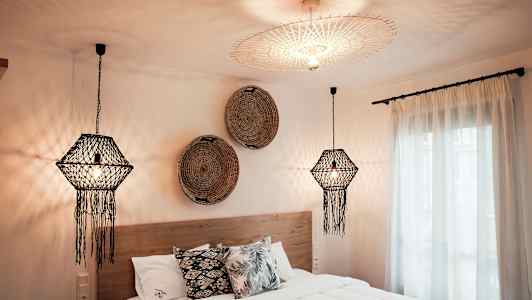 Et soverom med dekorative taklamper, en seng med puter og veggdekorasjoner. (AI-generert tekst)