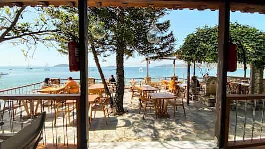 Uterestaurant med havsutsikt og trebord. (AI-generert tekst)