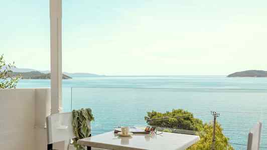 Utsikt mot havet fra en terrasse med bord og stoler. (AI-generert tekst)