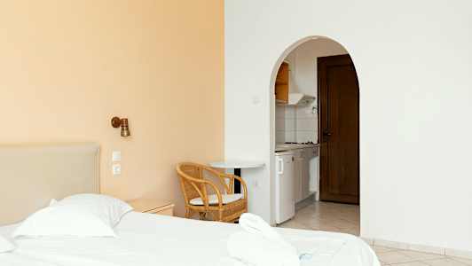 Et hotellrom med en seng, stol og et åpent kjøkken. (AI-generert tekst)