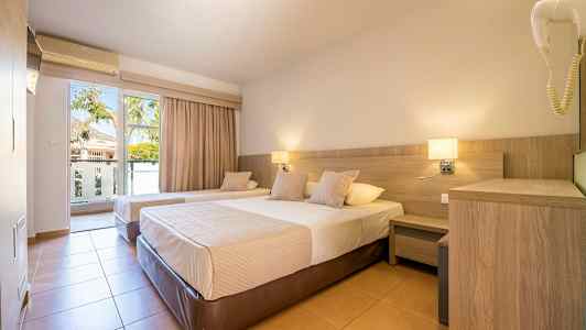 Et hotellrom med to enkeltsenger, nattbord og en balkongdør med utsikt. (AI-generert tekst)