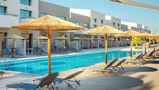 Utendørs svømmebasseng med solsenger og parasoller samt bygninger i bakgrunnen. (AI-generert tekst)