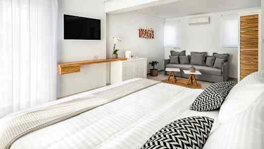 Et lyst, moderne hotellrom med seng, sofa og TV. (AI-generert tekst)