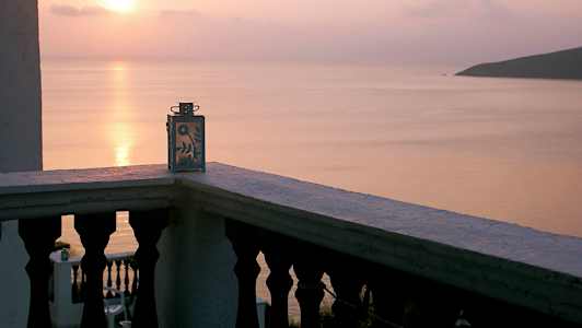 Utsikt fra en balkong med en dekorativ lyslykt, solnedgang over havet. (AI-generert tekst)