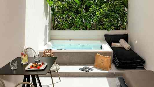 Et uteområde med et boblebad, solsenger og et bord med drikke og snacks. (AI-generert tekst)