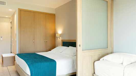 Hotellrom med dobbeltseng og enkeltseng, samt treskyvedør. (AI-generert tekst)