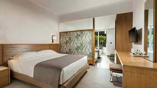 Et hotellrom med en seng, trebord og en moderne innredning. (AI-generert tekst)