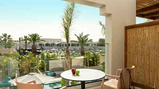 Utsikt fra en terrasse med bord, stoler og dekorativ vegetasjon. (AI-generert tekst)