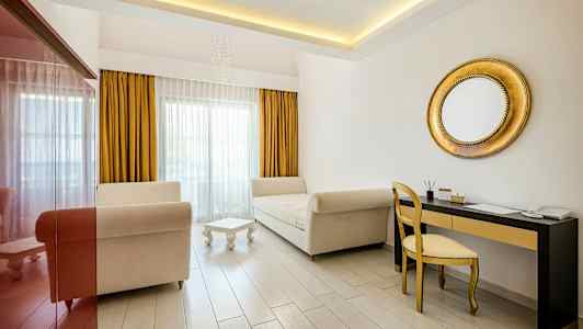 Bilde av et lyst rom med to sofaer, et lite bord, en gullfarget speil og skrivebord med stol. (AI-generert tekst)