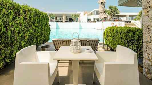 Bord og stoler foran et basseng. (AI-generert tekst)