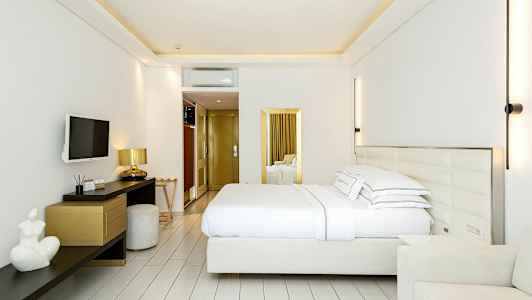 Et moderne hotellrom med en dobbeltseng, veggmontert TV, skrivebord og stoler. (AI-generert tekst)