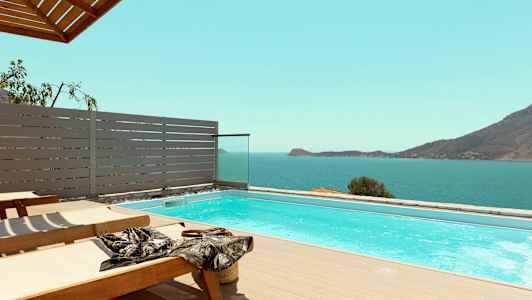 Solstoler ved et basseng med utsikt over havet og fjell. (AI-generert tekst)
