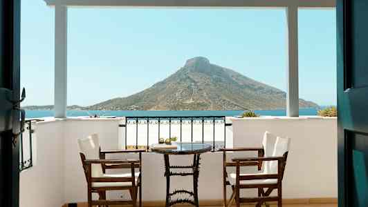 Veranda med to stoler og et bord, utsikt mot havet og fjell. (AI-generert tekst)