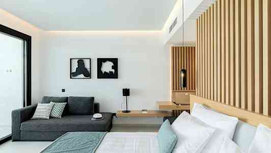 Et moderne hotellrom med en seng, en sofa og en vegg med trepanel. (AI-generert tekst)