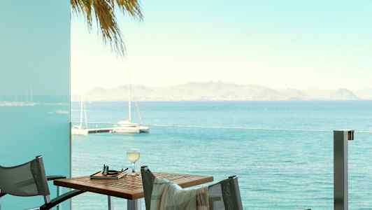 Utsikt over havet fra en terrasse med bord og stoler. (AI-generert tekst)