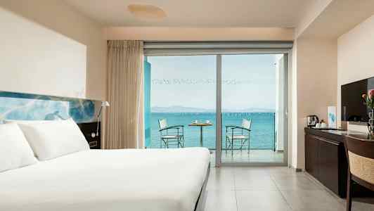 Et hotellrom med en stor seng, et skrivebord og en balkong med havutsikt. (AI-generert tekst)