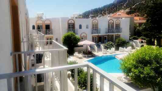 Hotellanlegg med et svømmebasseng og solsenger omgitt av grønne planter. (AI-generert tekst)