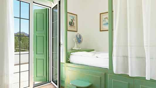 Et rom med grønne møbler og en dør som fører til en balkong. (AI-generert tekst)