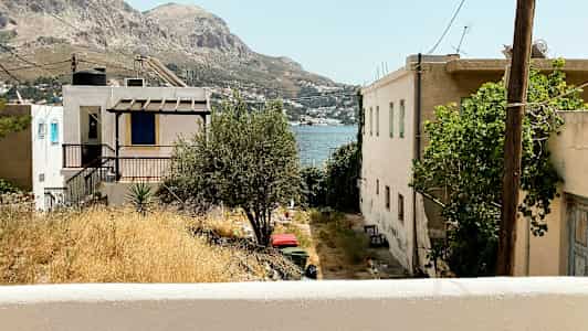 Utsikt over hus og uteplasser med fjell og hav i bakgrunnen. (AI-generert tekst)