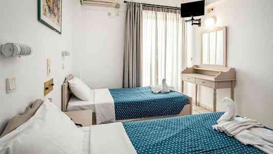 To enkeltssenger med blåprikkete overkast i et lyst hotellrom. (AI-generert tekst)