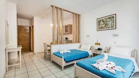 Et hotellrom med to enkeltsenger, blå sengtepper og dekorerte håndklær. (AI-generert tekst)