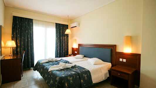 Bilde av et hotellrom med en dobbeltseng, skrivebord og nattbord. (AI-generert tekst)