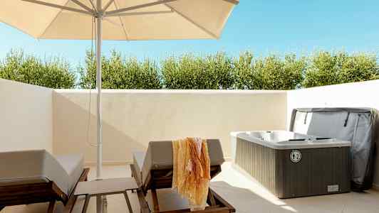 Utendørsområde med solsenger, parasoll og et boblebad. (AI-generert tekst)