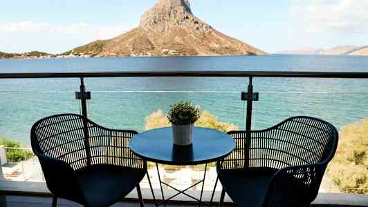 Utsikt over havet fra en balkong med to stoler og et bord. (AI-generert tekst)