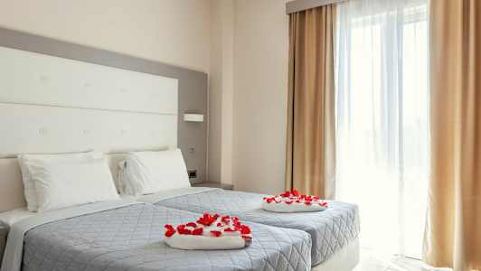 Et hotellrom med to enkeltsenger dekorert med røde roseblader. (AI-generert tekst)