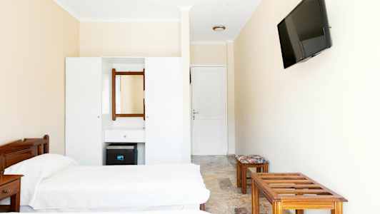 Et hotellrominteriør med to enkeltsenger, en kommode med speil og en veggmontert TV. (AI-generert tekst)