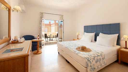 Hotellrom med dobbeltseng, sittegruppe, vindu og møblert terrasse. (AI-generert tekst)