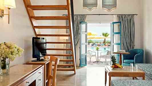 Et romslig hotellrom med tremøbler, en tretrapp, og en dør som leder ut til et basseng. (AI-generert tekst)