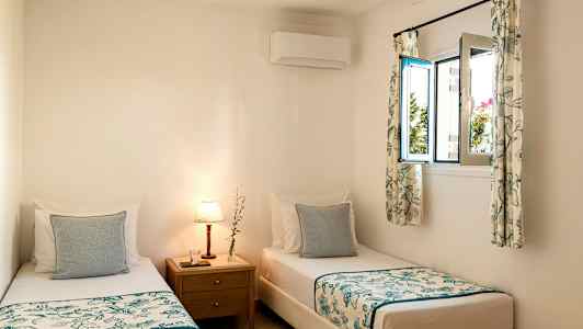 Rom med to enkeltsenger og et nattbord med lampe. (AI-generert tekst)