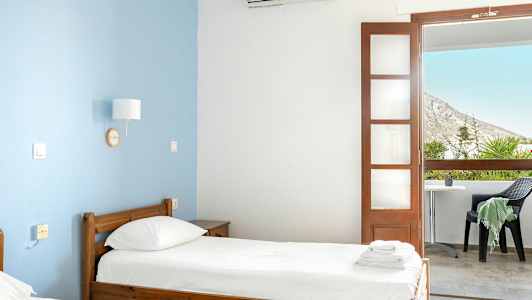 Et hotellrom med to enkeltsenger og en balkong med utsikt. (AI-generert tekst)