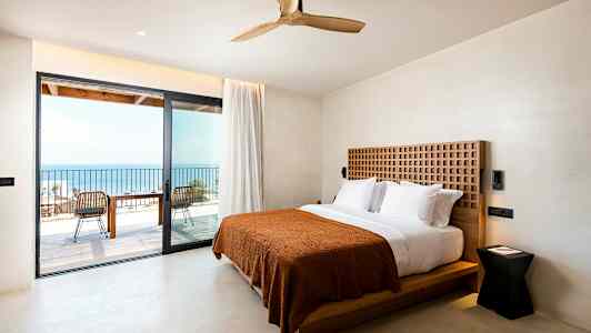 Hotellrom med dobbeltseng og utgang til en balkong med havutsikt. (AI-generert tekst)