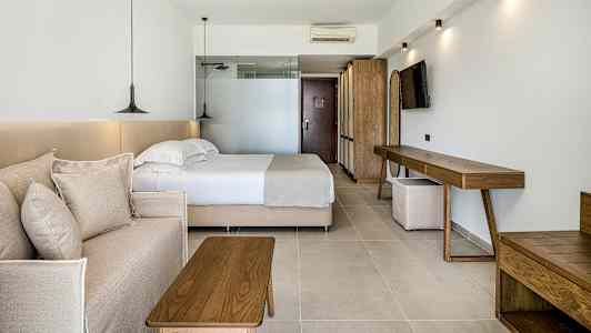 Et hotellrom med en seng, en sofa og tremøbler. (AI-generert tekst)