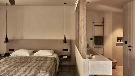 Et soverom med en dobbeltseng, en skillevegg som separerer et bad med servant og håndkleholder. (AI-generert tekst)