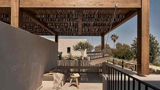 En utendørs terrasse med en trepergola, en hengekøye og en sittegruppe med bord. (AI-generert tekst)