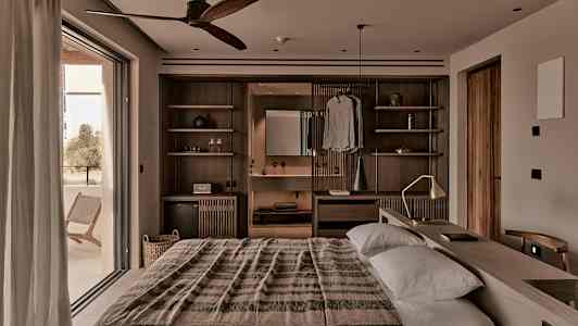 Et varmt innredet soverom med dobbeltseng, tredetaljer og en bred balkongdør. (AI-generert tekst)