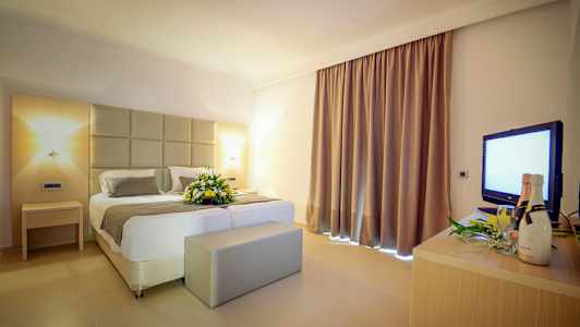 Hotellrom med en dobbeltseng og en blomsterdekorasjon. (AI-generert tekst)