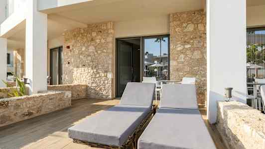 To solsenger på en steinlagt uteplass foran bygning med steinfasade. (AI-generert tekst)