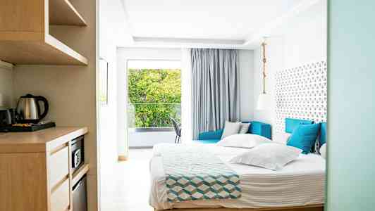 Bilde av et lyst hotellrom med seng, sofa og vindu med utsikt. (AI-generert tekst)