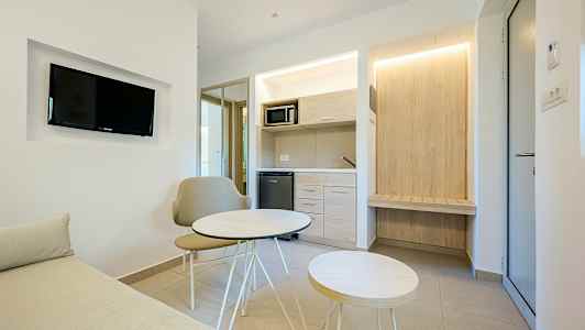 Et moderne hotellrom med en liten sittegruppe og tekjøkken. (AI-generert tekst)