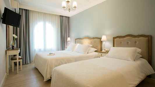 Hotellrom med to enkeltsenger, lys innredning og vindu med gardiner. (AI-generert tekst)