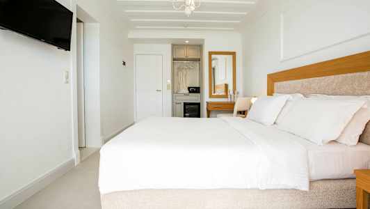 Moderne hotellrom med bred seng, hvitt interiør og tremøbler. (AI-generert tekst)