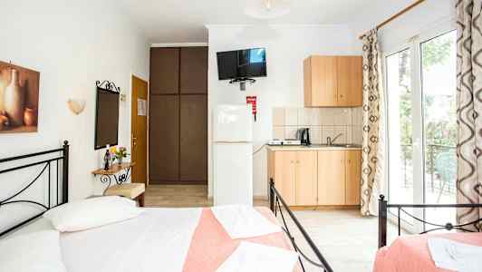 Et lyst og luftig soverom med dobbeltsenger, en liten kjøkkenkrok og tilgang til en balkong. (AI-generert tekst)