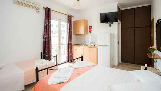 Hotellrom med tre senger, garderobe, klimaanlegg og tekjøkken. (AI-generert tekst)