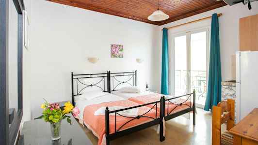 Et hotellrom med to enkeltsenger og en vase med blomster på et bord. (AI-generert tekst)